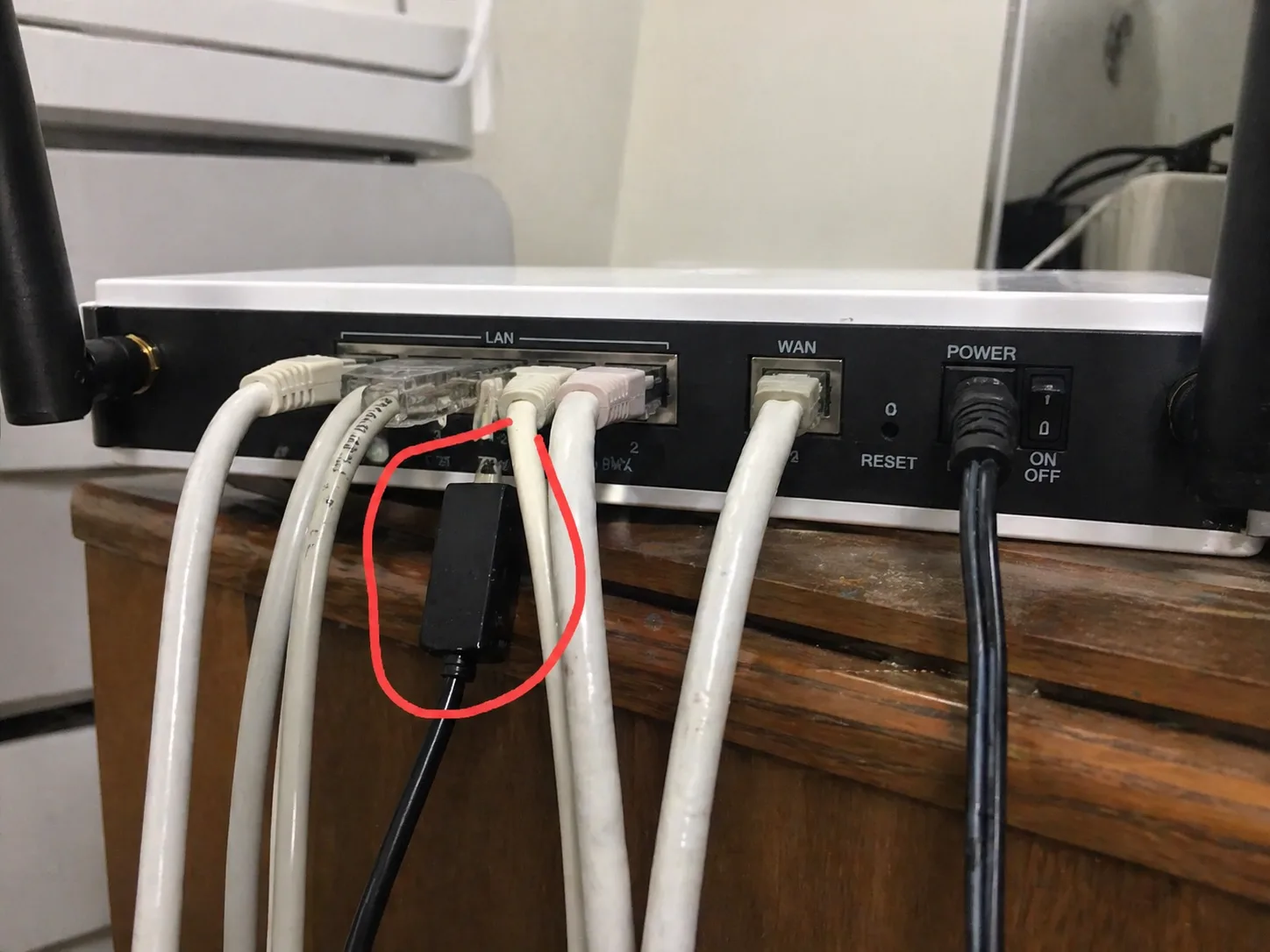 ケーブルが挿さったルーターの背面——LAN に割り込ませた不正な機器を赤丸で示している